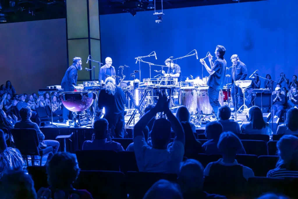 Sō Percussion ensemble and audience under blue lighting at Beeple Studios, photographed by Camology Media